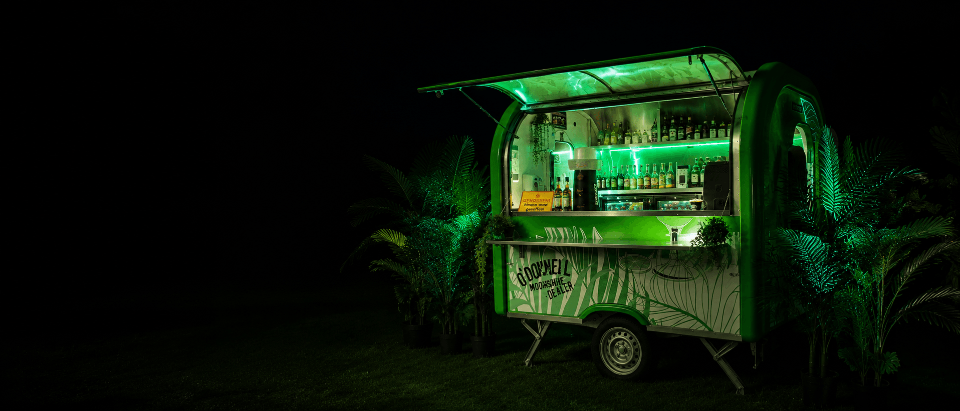 Grün beleuchtete mobile Cocktailbar bei Nacht